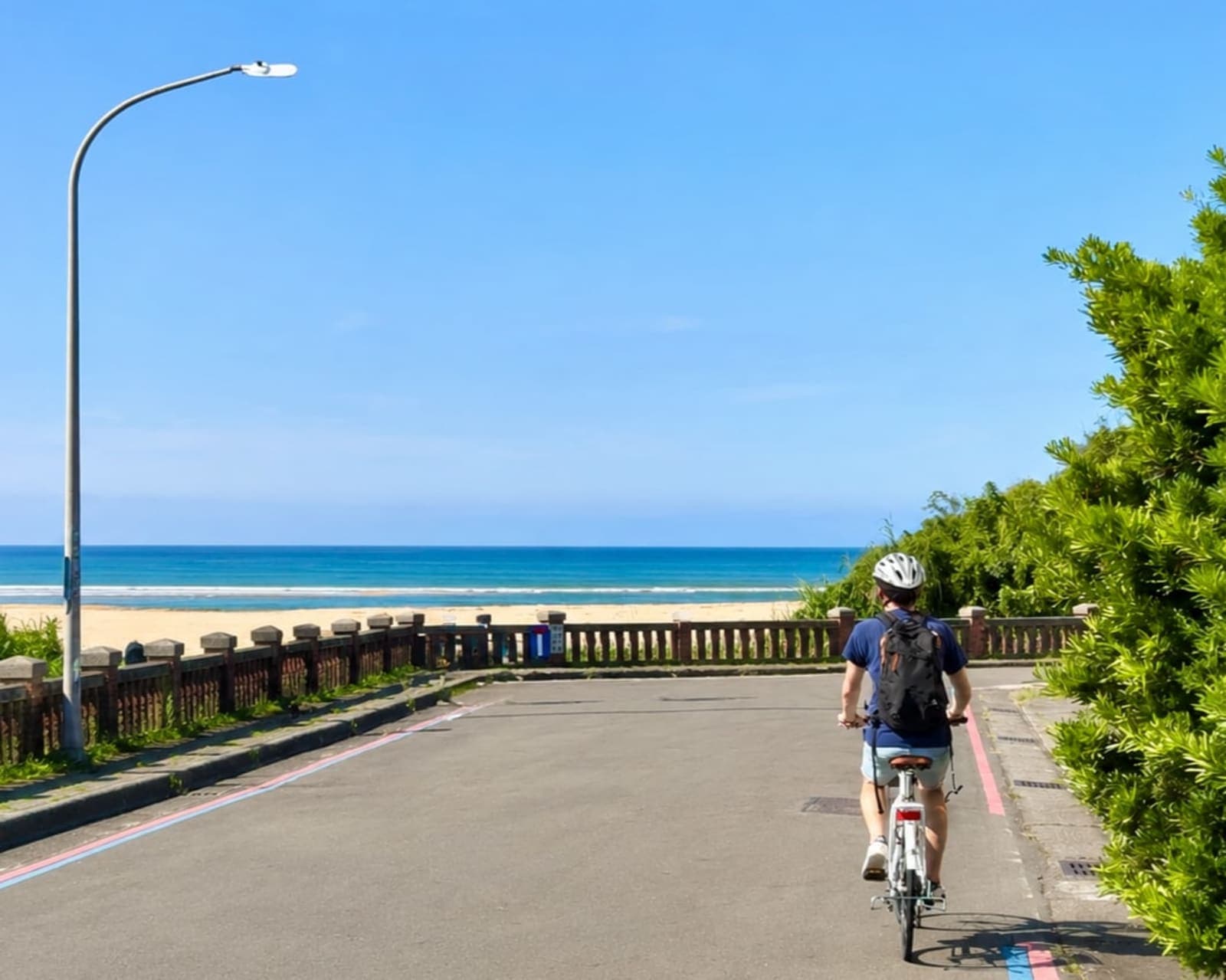 騎單車行經濱海步道,前方是金色沙灘與湛藍海洋